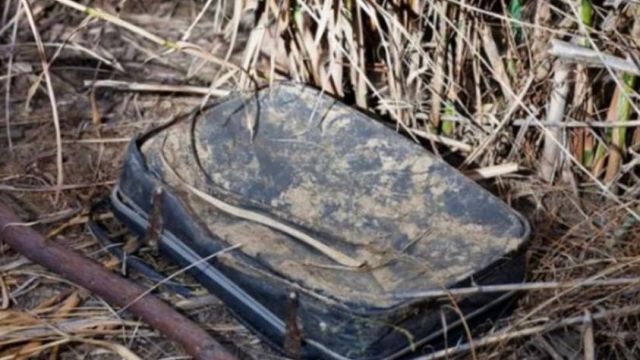 HT1. This woman came across an old, filthy luggage in a bush